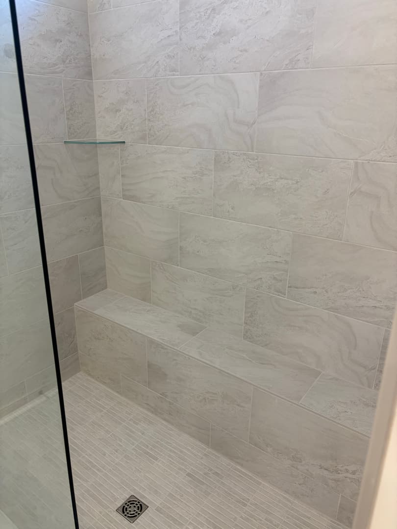 Tiled walk-in shower with bench and glass door