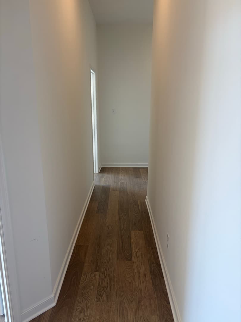 Hallway with clean hardwood floor and baseboards